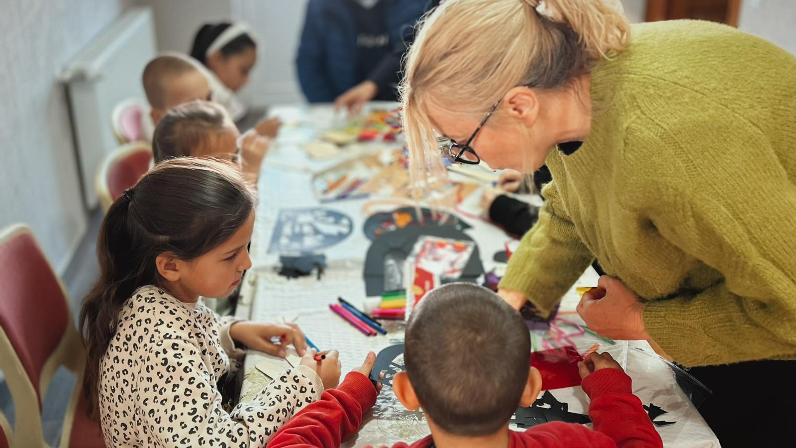 Volunteer helping children with craft activities